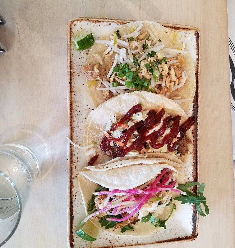 The Peached Tortilla signature dishes Banh Mi Tacos, Southern Fun (braised brisket, kale, bean sprouts), Luchea Cauliflower, Dan Dan Noodles
